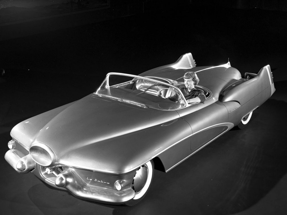 black and white photo of a 1950s Buick Le Sabre concept car with a woman sitting in the driver's seat.
